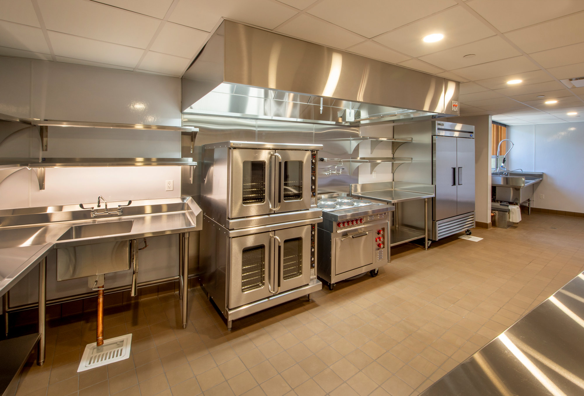 stainless steel commercial kitchen with benches and hood