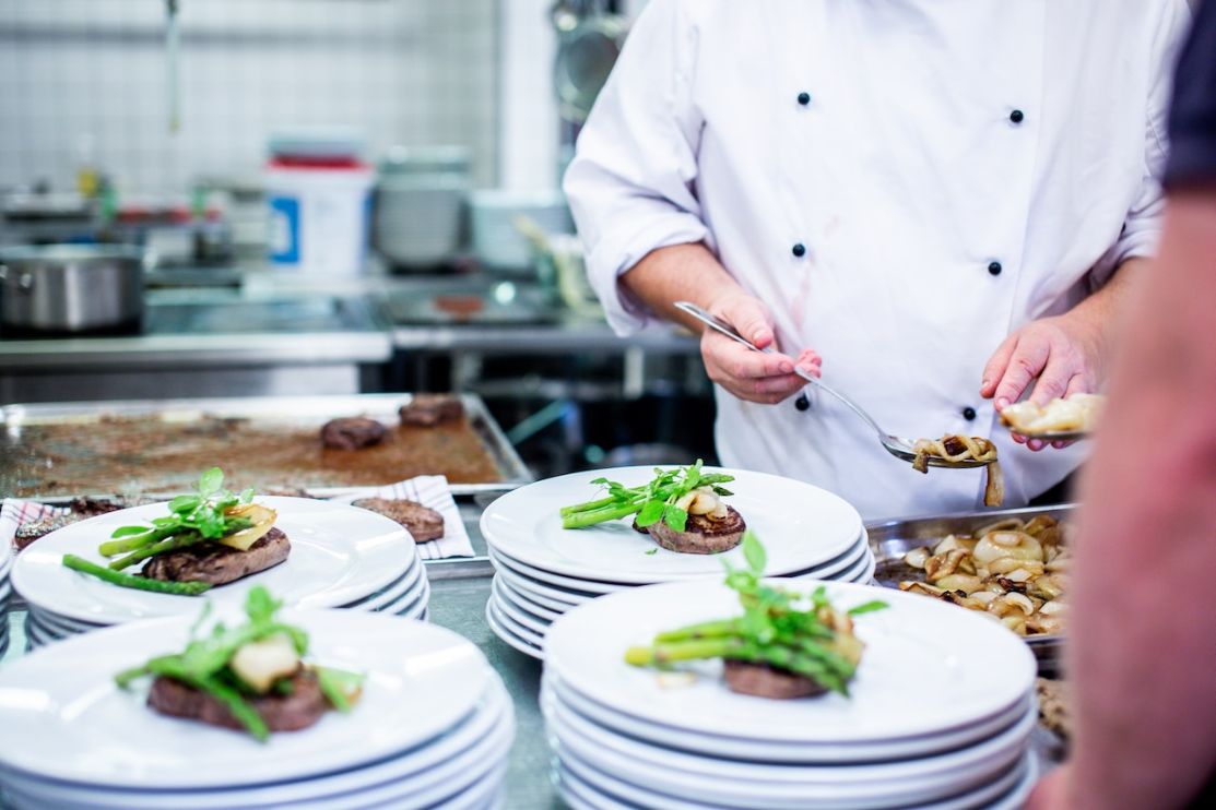 Chef plating up food in commercial kitchen